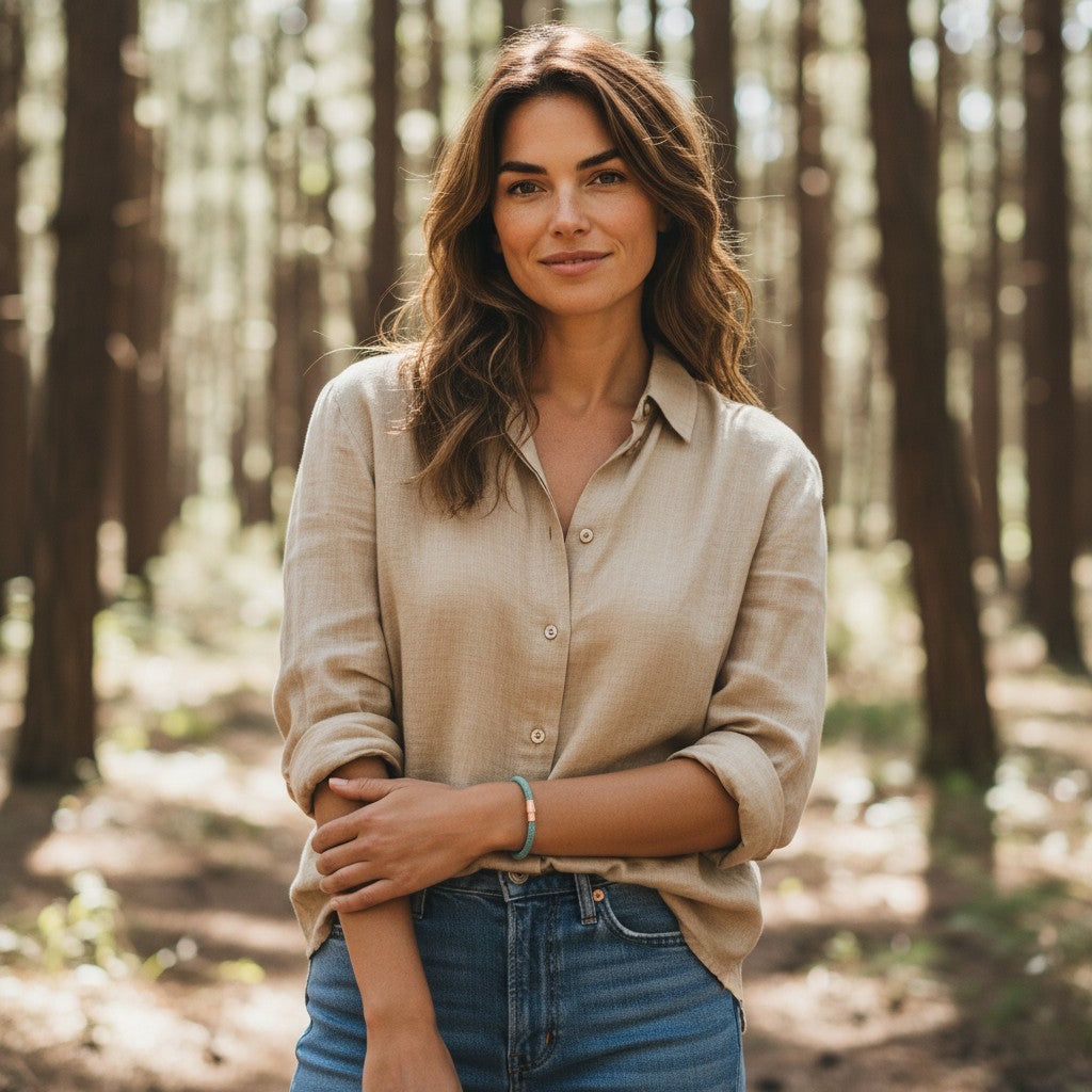 A brunette woman wearing a handcrafted sky blue cork bracelet while standing in a green forest setting, showcasing unisex adult outdoor style by Every Soul Counts.